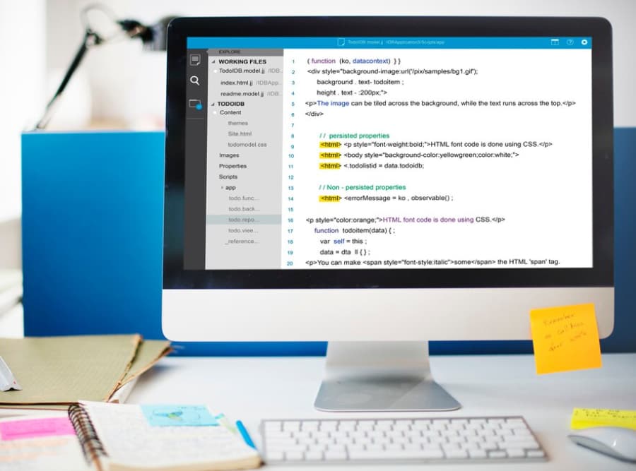 Close-up of code on a computer screen with sticky notes