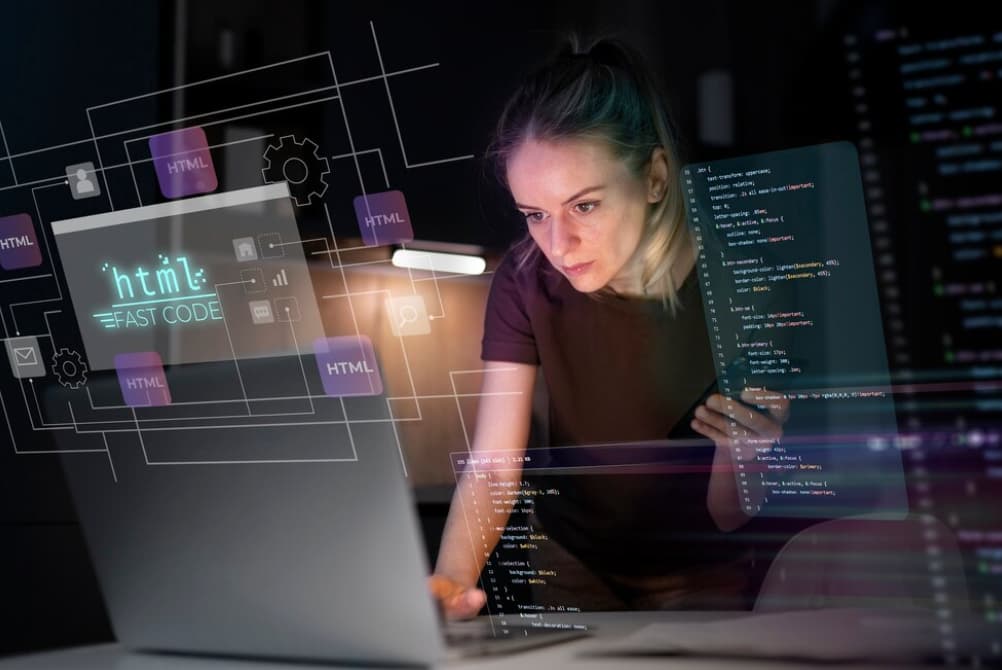 A focused woman coding on a laptop with virtual HTML graphics around her