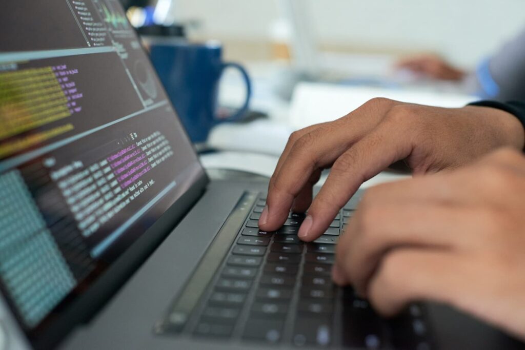 Man's hands on a laptop keyboard writing code